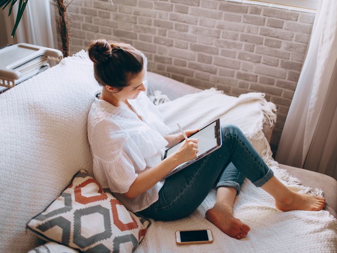 woman on a couch browsing online with an ipad